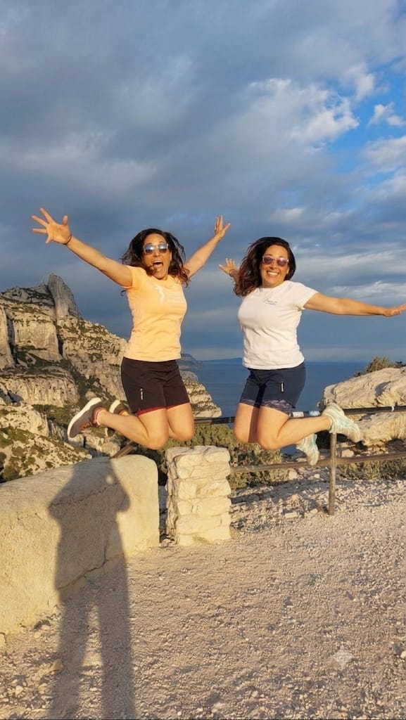 Deux sœurs en plein saut joyeux dans les Calanques au coucher du soleil